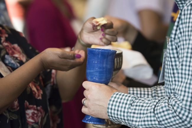 Hands dipping break into communion cup