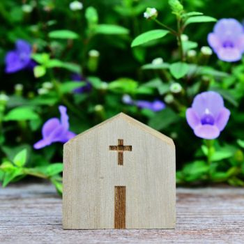 wooden toy church near purple flowers