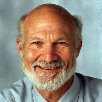 Stanley Hauerwas headshot in blue shirt and red and green tie